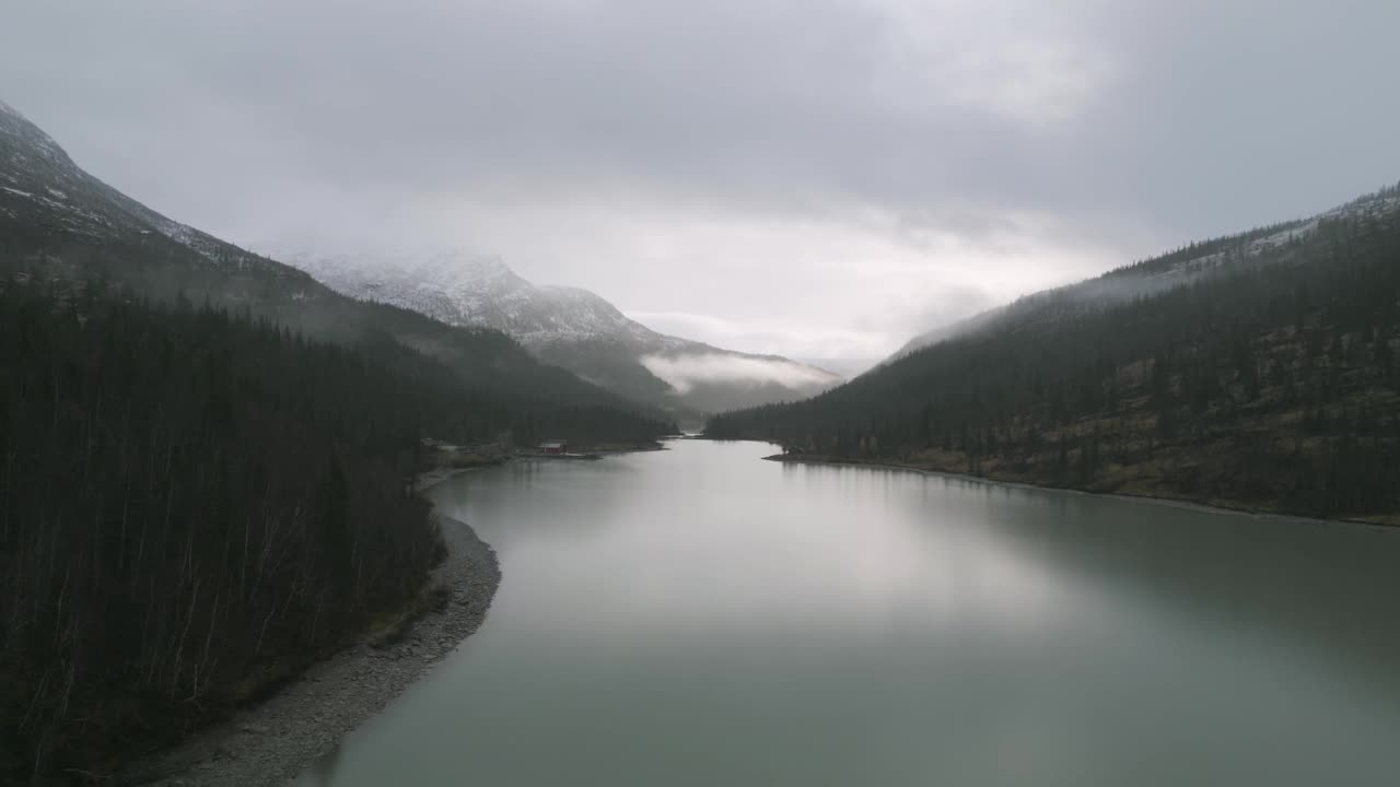 雾蒙蒙的挪威Svartisvatnet湖，周围是积雪覆盖的山脉，天空多云视频素材