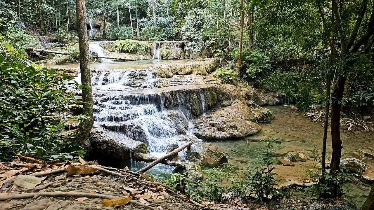 宁静的瀑布在四面湾国家公园，北碧府与郁郁葱葱的绿色植物和宁静的水流视频素材