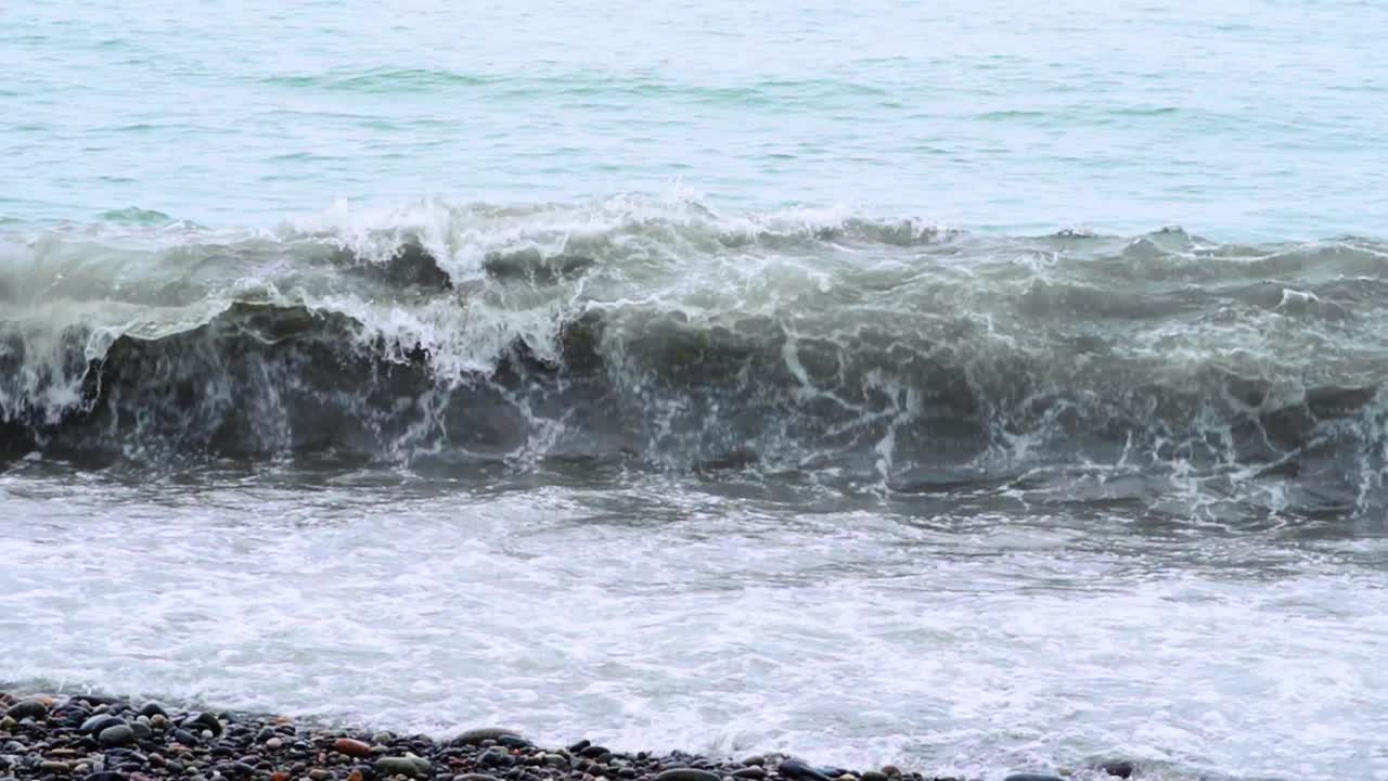 汹涌的海浪拍打着卵石海岸线，展示着海洋的美丽和力量。视频素材