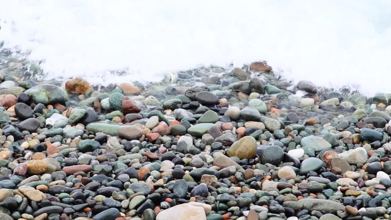 汹涌的海浪拍打着卵石海岸线，展示着海洋的美丽和力量。视频素材