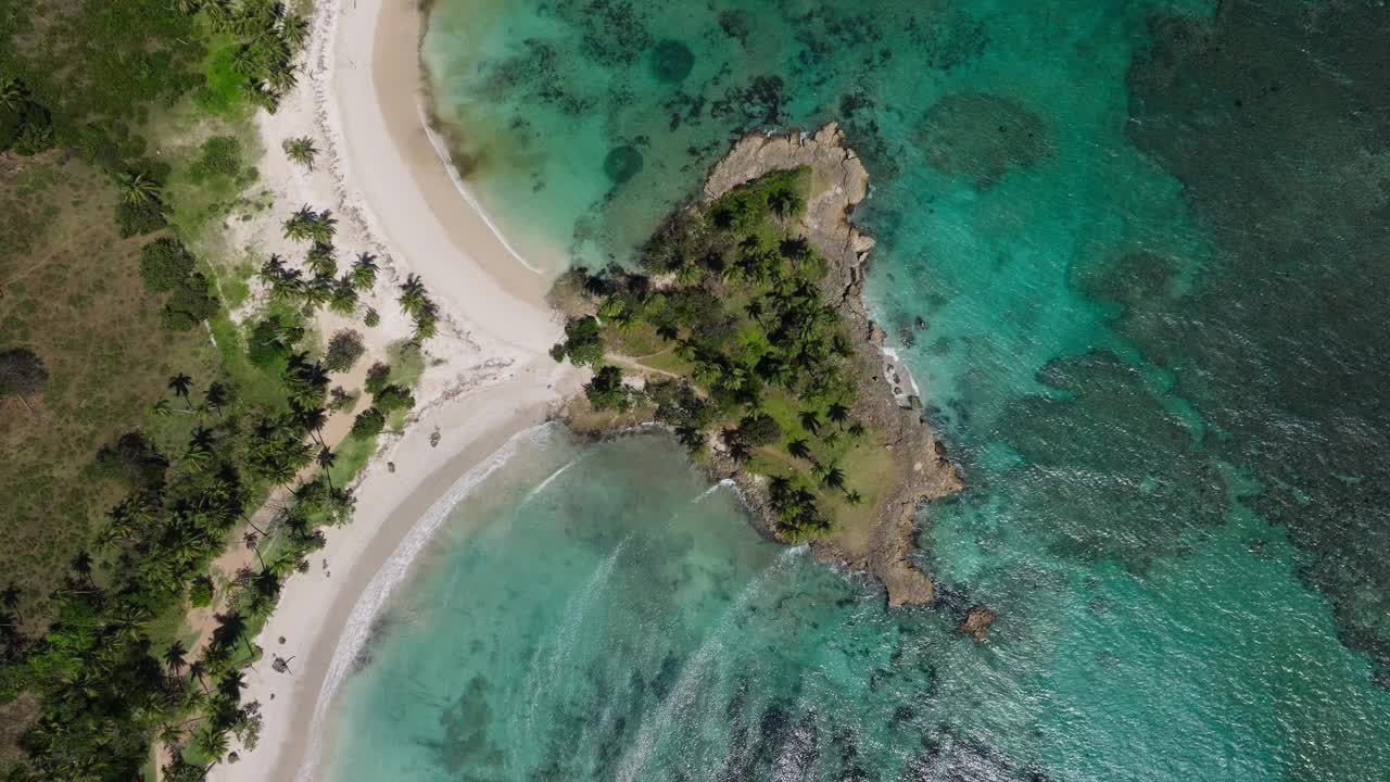 海浪翻滚到珊瑚礁上的沙湾，热带棕榈树和白色沙滩，无人机鸟瞰视频素材