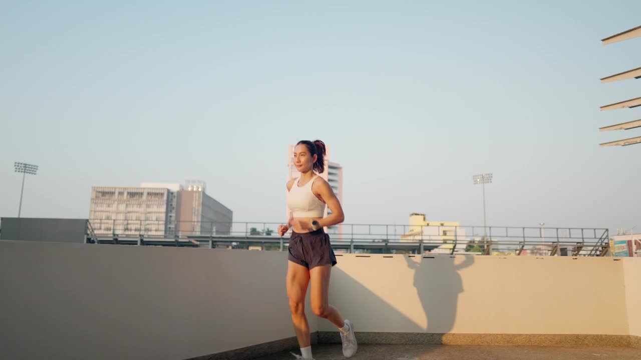 一个女人在屋顶上跑步，背景是城市的天际线视频素材