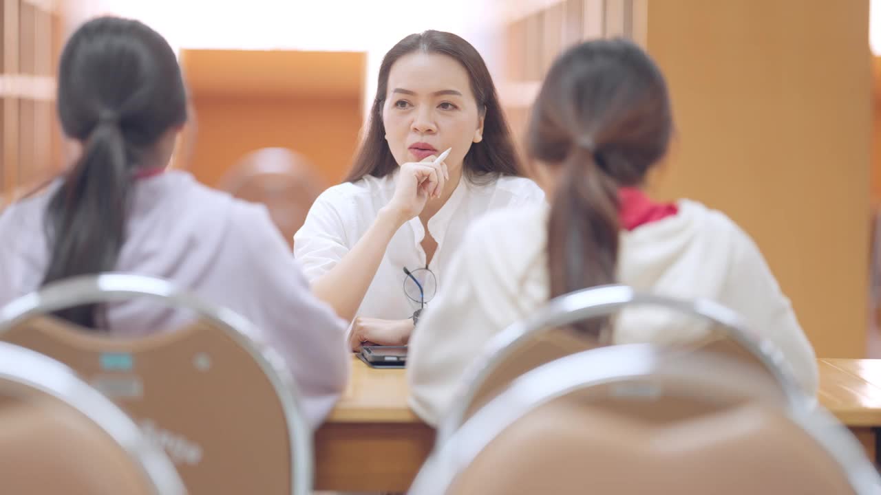 三个女人坐在一张桌子旁，其中一个戴着眼镜视频素材