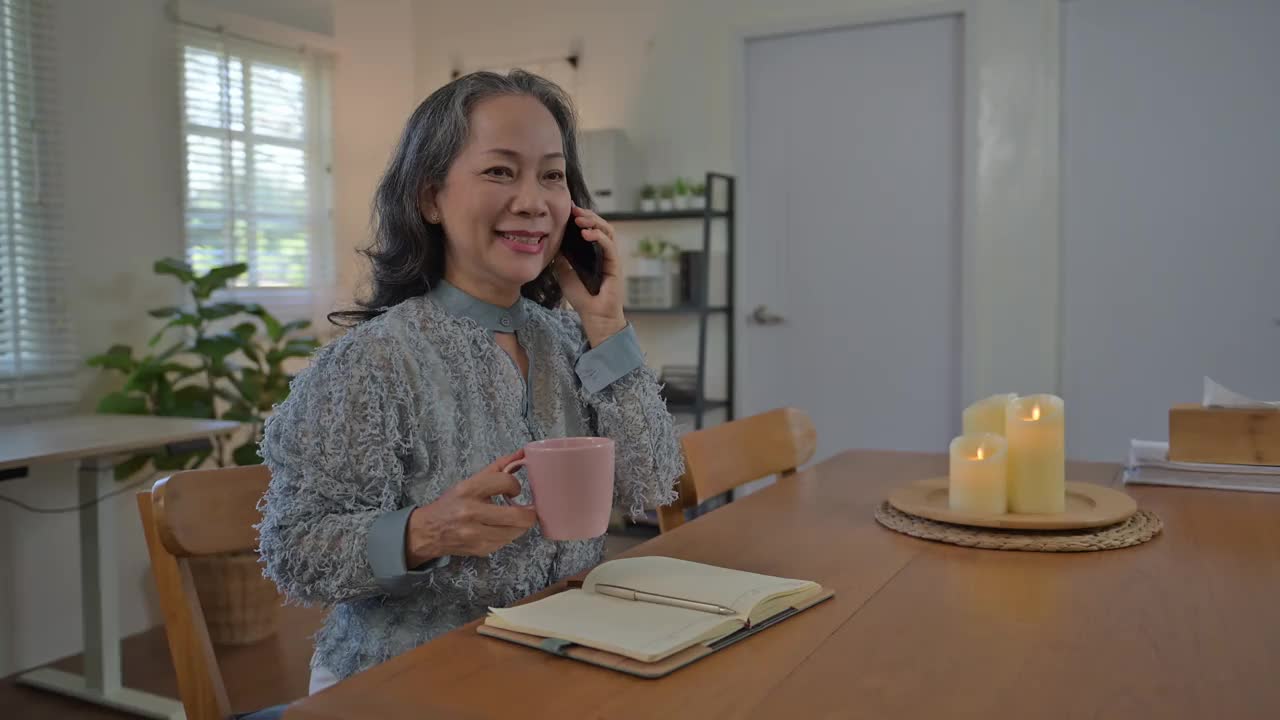 漂亮的亚洲老太太在客厅接电话。视频素材