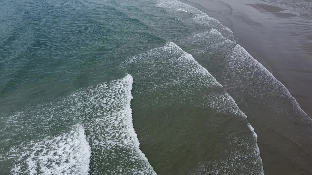 一个荒凉的海滩，有潮湿的沙滩和美丽的海浪。浪花上泛起白色的泡沫。海景俯视图，无人机视频。大西洋上的波浪。视频素材