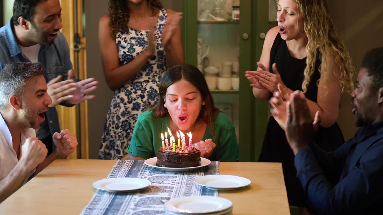 年轻女子吹灭生日蛋糕上的蜡烛视频素材