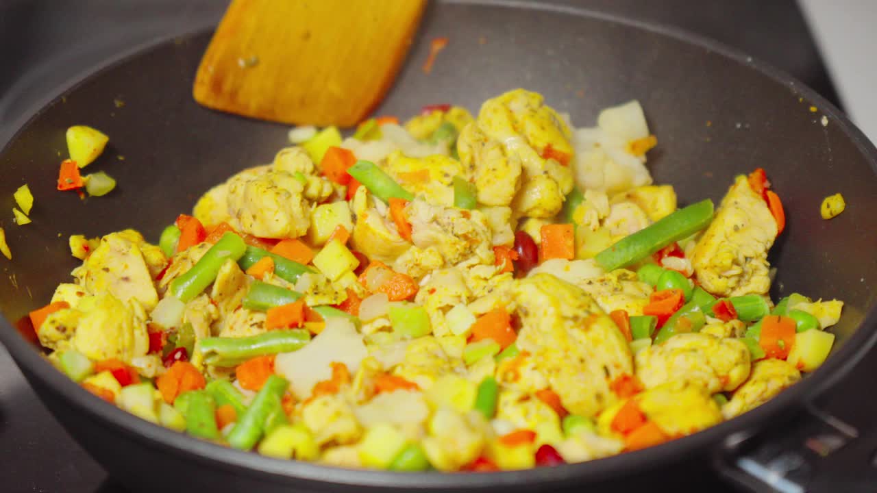 多汁的鸡肉块在新鲜蔬菜的彩虹中咝咝作响，充满了烹饪的活力。视频素材