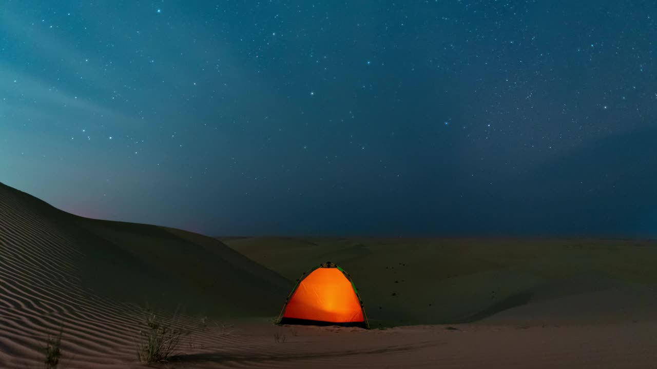 在沙漠野外露营时，星空在夜空中移动。视频下载