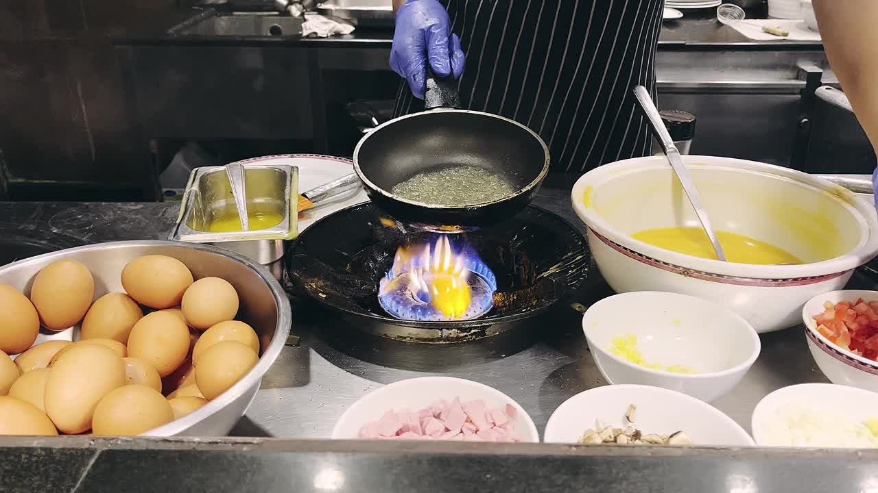 酒店专业厨师在现代化餐厅厨房内，将各种食材放入煎锅中烹煮。视频下载