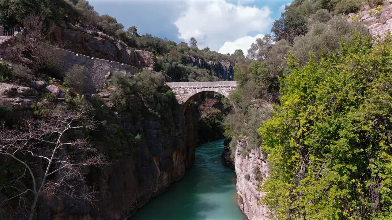 俯瞰横跨Köprülü峡谷的古罗马桥，下面是绿松石色的河流，周围是郁郁葱葱的绿色植物，土耳其安塔利亚。视频素材