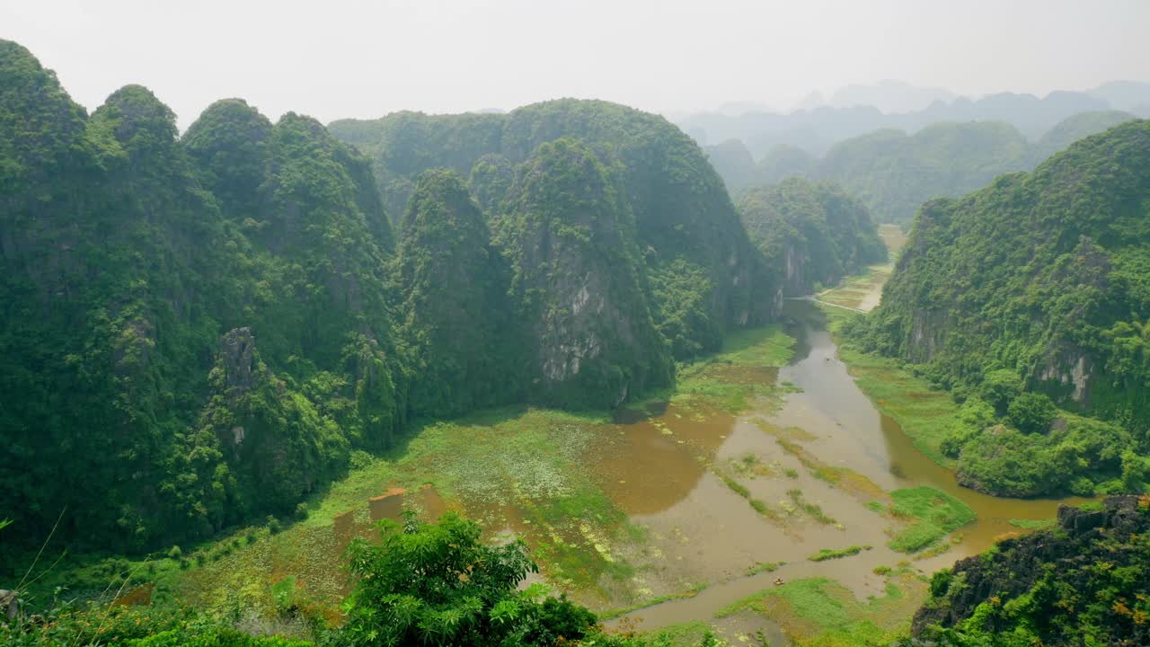 在Cuc Phuong国家公园，宁静的河流和小船流过石灰岩悬崖视频素材