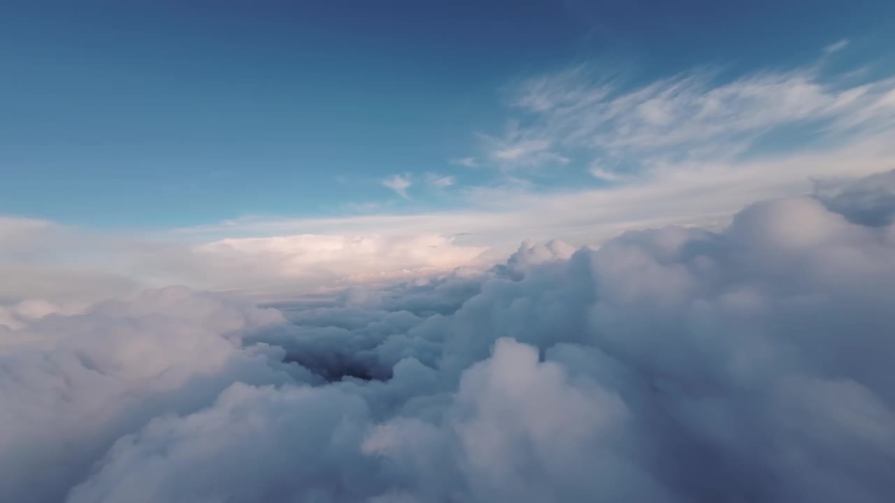 晚霞在明亮的蓝天上。在蓬松柔软的云层之上，在无人机或RC飞机上缓慢飞行视频素材