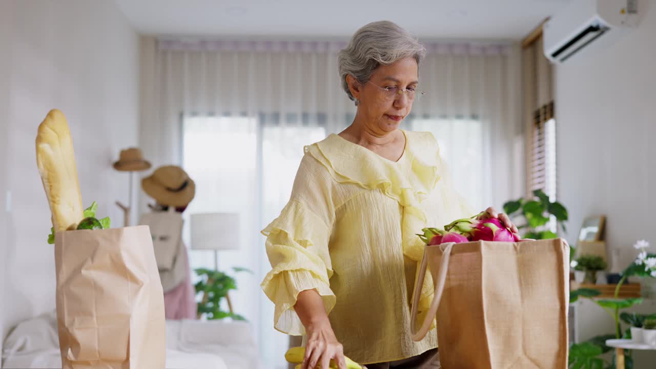 在厨房里为丈夫准备有机食品时，这位年长的女性拥抱着爱和健康的纽带。健康生活和亲情的美好写照。视频素材