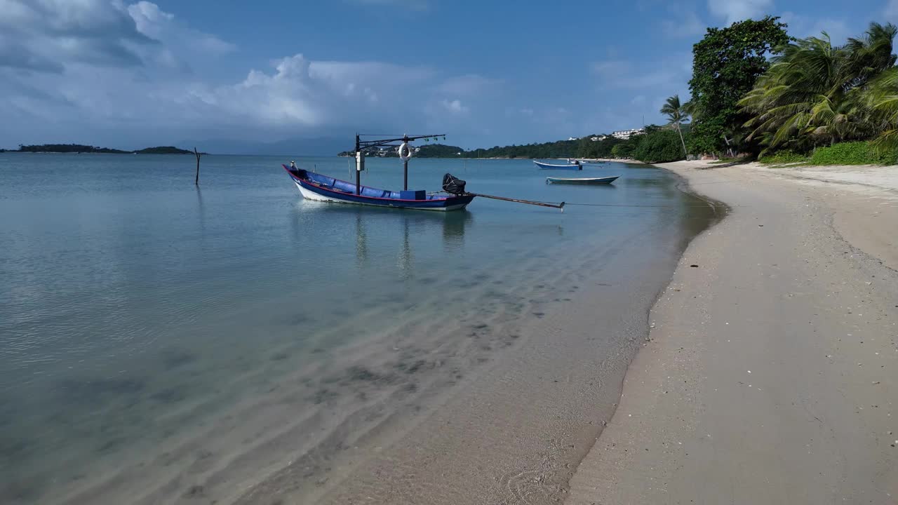 宁静的海滩景色与停泊的船在苏梅岛的清澈的海水，阳光明媚的一天视频素材