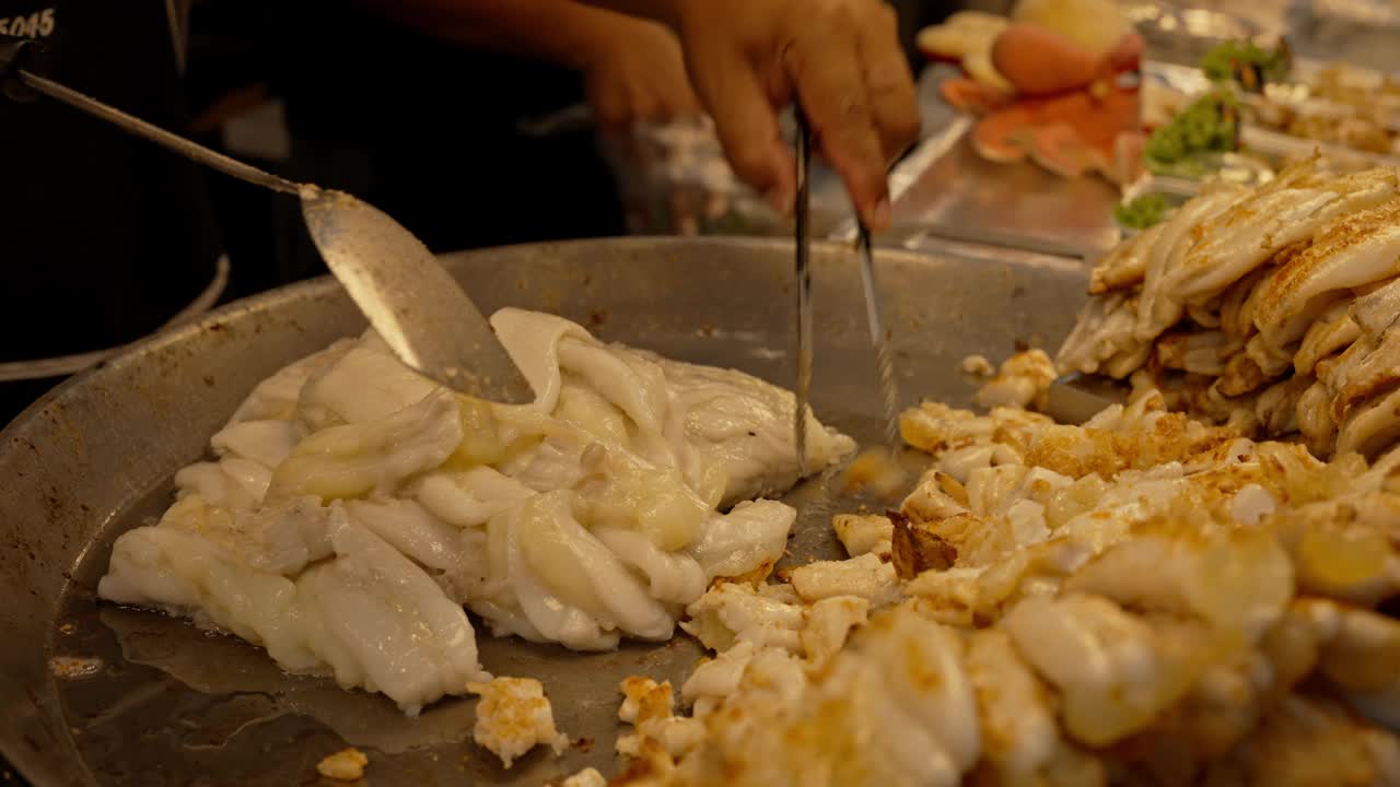 亚洲街头小吃店的厨师正在烹调炒鱿鱼蛋，准备在本地市场出售。视频下载