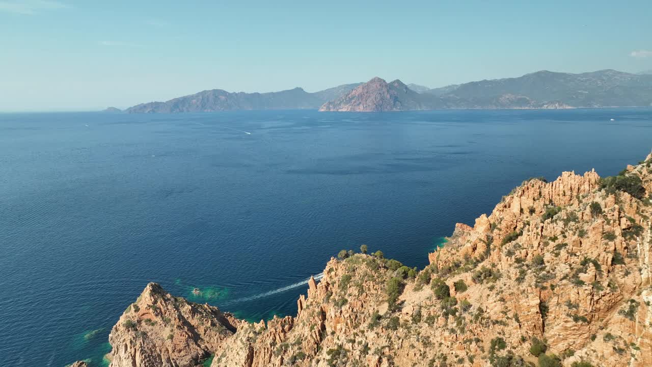 科西嘉岛的吉罗拉塔高尔夫，有一艘孤独的船，清澈的蓝色海水和崎岖的悬崖，阳光明媚的天空下，鸟瞰图视频素材