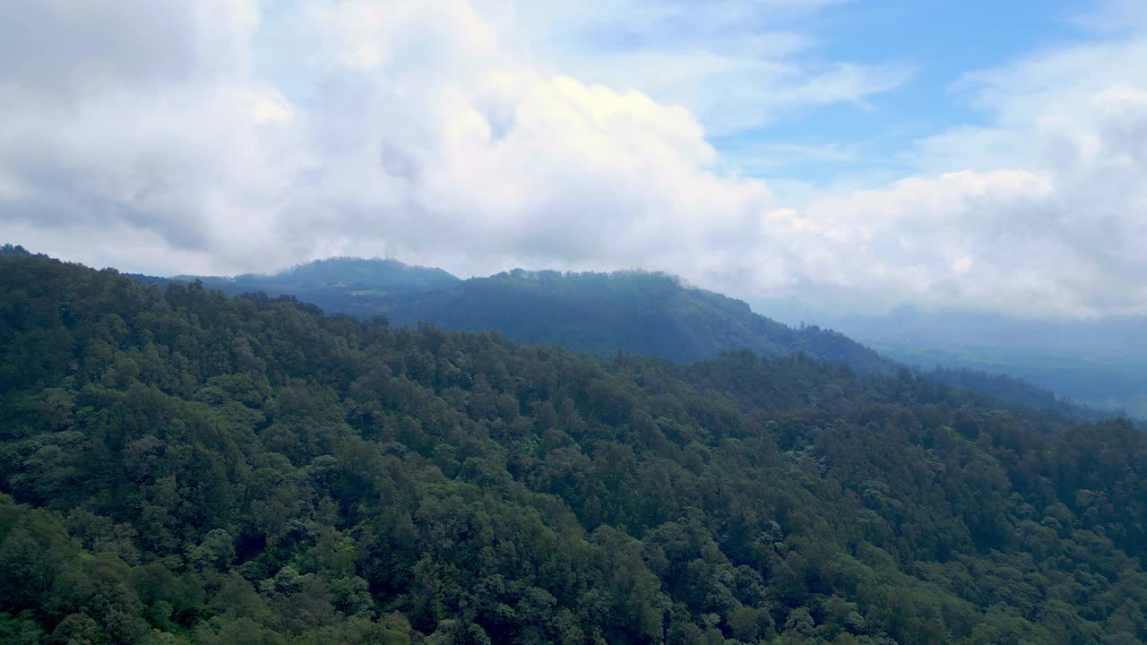 空中无人机在绿色森林树木在美丽的山脉亚洲的土地。印度尼西亚茂密的森林和丛林自然之旅。雄伟的生态和古老亚洲林地的田园环境视频素材