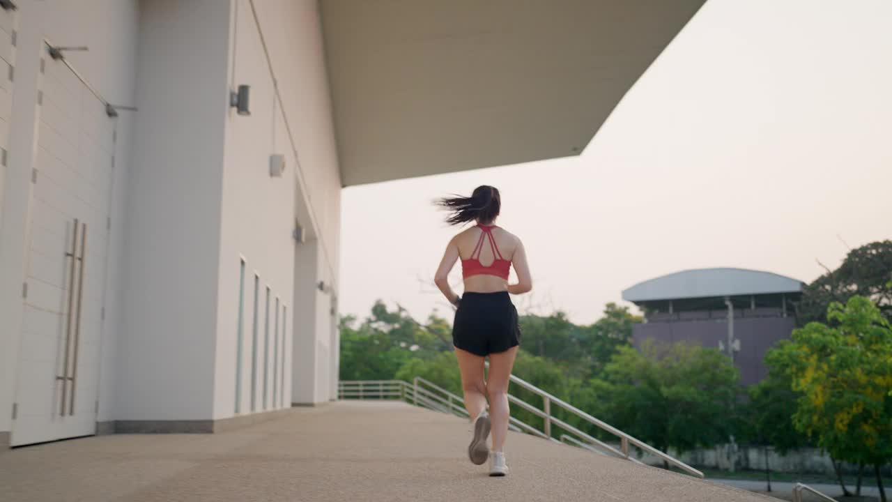 一位妇女在建筑物前的人行道上奔跑视频素材