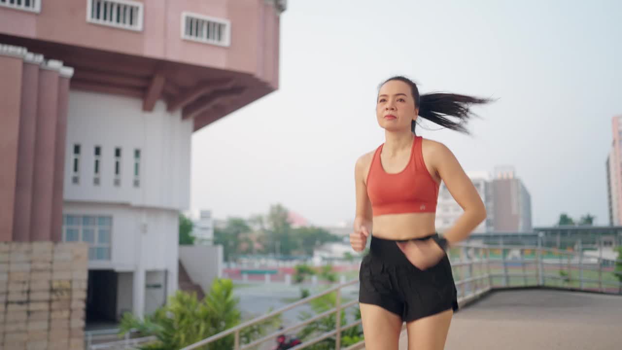 一位妇女在建筑物前的人行道上奔跑视频素材