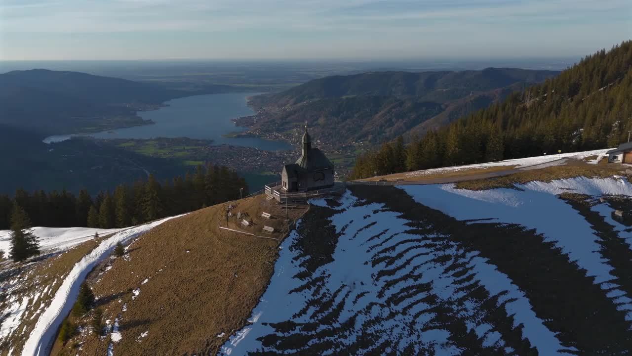 Kapelle Heilig Kreuz Rottach-Egern Tegernsee。Wallbergkapelle在Wallberg山上俯瞰Tegernsee湖和山脉，在阳光明媚的春天，日落时下雪。阿尔卑斯山山顶上的教堂。视频素材