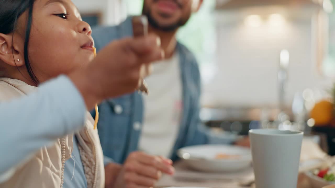 父亲、孩子和一个女孩在家里的餐厅里和她的家人一起吃意大利面。食物，孩子和父母围坐在桌子旁吃饭，在家里吃晚餐视频素材