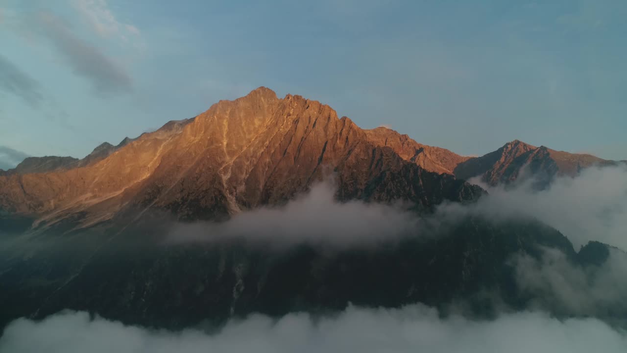 落日时分，无人机在意大利阿尔卑斯山上空拍摄。高山峰的景色。温暖的阳光照射在黄昏的山峰上。群山环绕的梦幻云景。视频素材