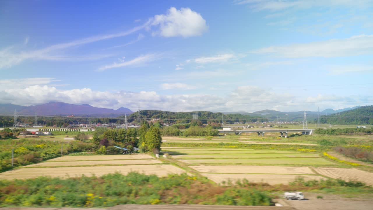 广角视角的农业地区的东北地区，日本以其丰富的农田和风景秀丽而闻名。宁静的乡村风景，蜿蜒的河流，广阔的田野，远处的山脉，湛蓝的天空和淡淡的云。视频下载