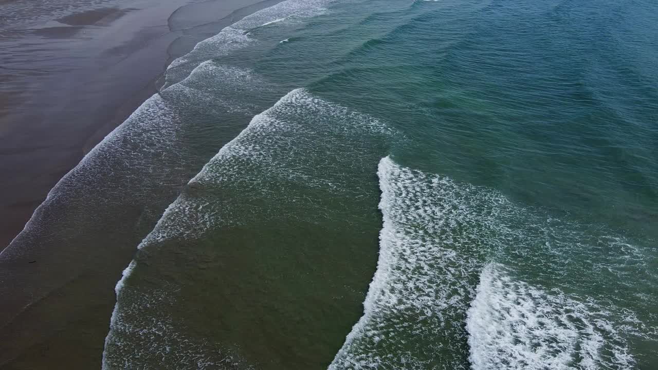 一个荒凉的海滩，有潮湿的沙滩和美丽的海浪。浪花上泛起白色的泡沫。海景俯视图，视频。大西洋上的波浪。视频素材