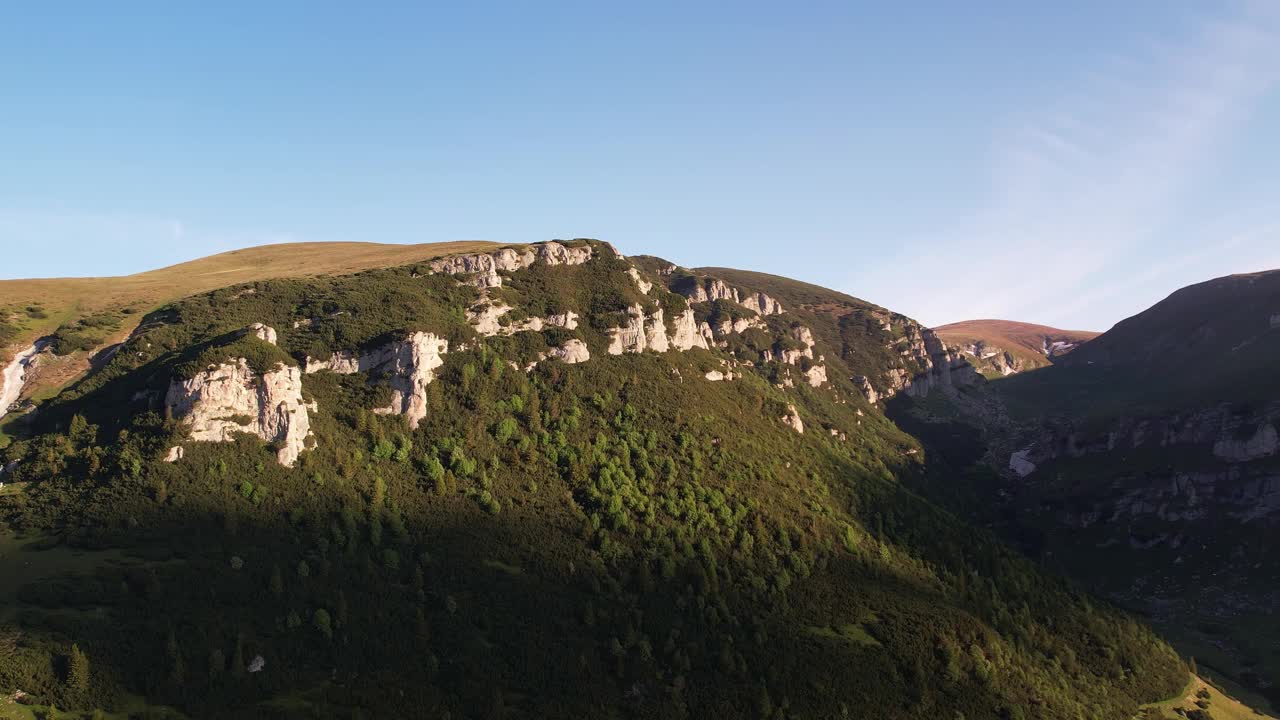 日出辉映在碧溪山的悬崖上，绿油油的树叶，航拍视频素材