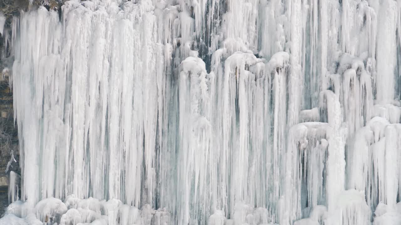 冰冻瀑布的特写与冰冷的岩石和流动的水。冰天雪地的冬日景观。神奇的大自然冬天。纯净的冰川水视频素材