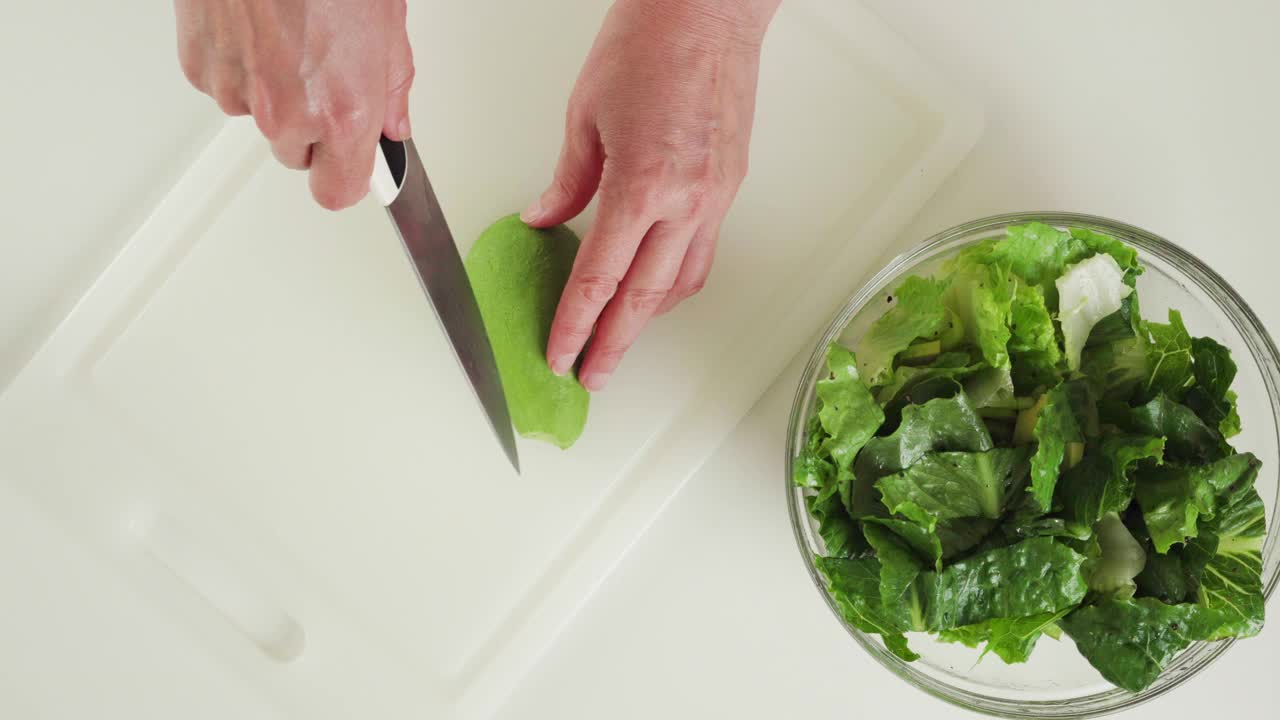 生菜，新鲜牛油果，芹菜和柠檬橄榄油调味沙拉食谱。厨房桌子上的食材特写，平放视频素材