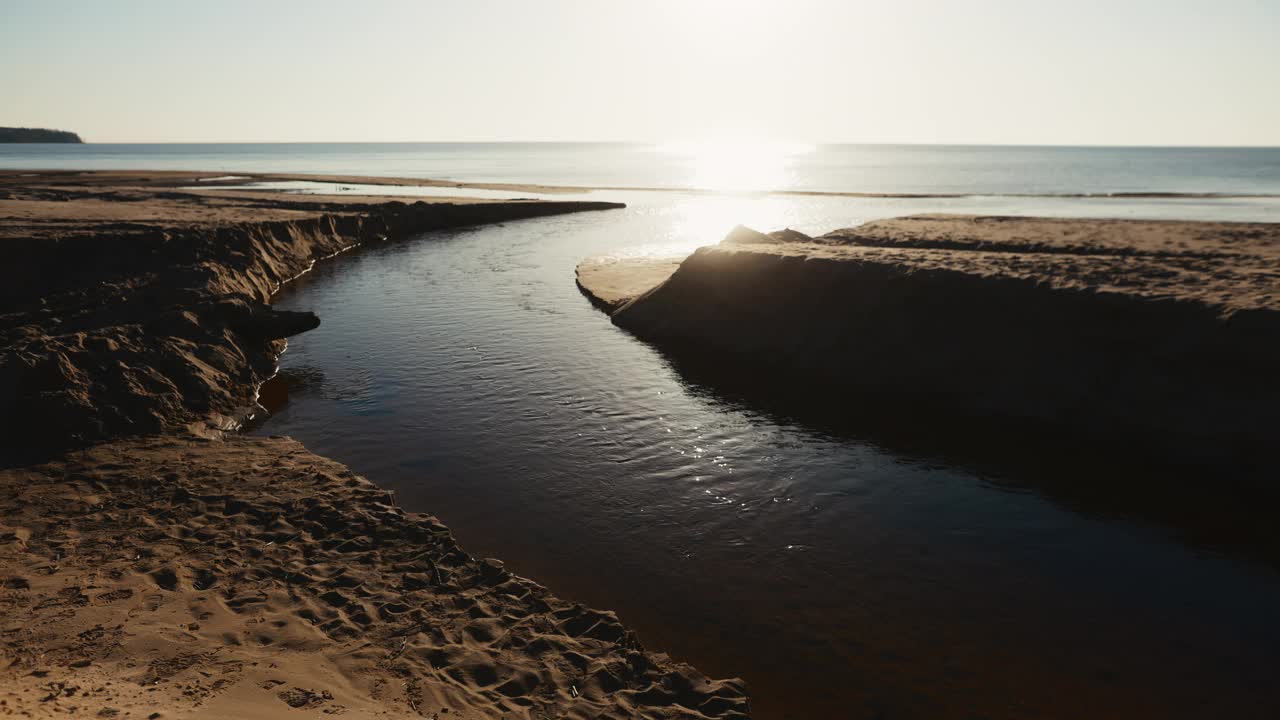 在晴朗的天空下，海水平静地流过海边的沙滩视频素材