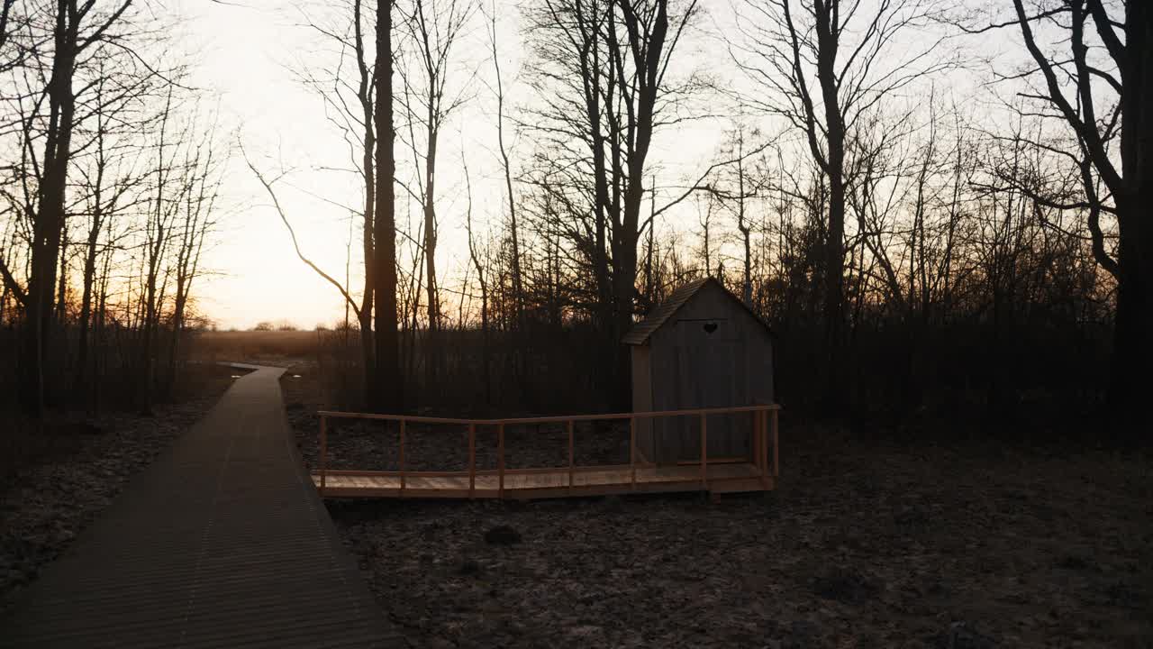 夕阳下的木质外屋，门上有心形标志，被树木环绕视频素材