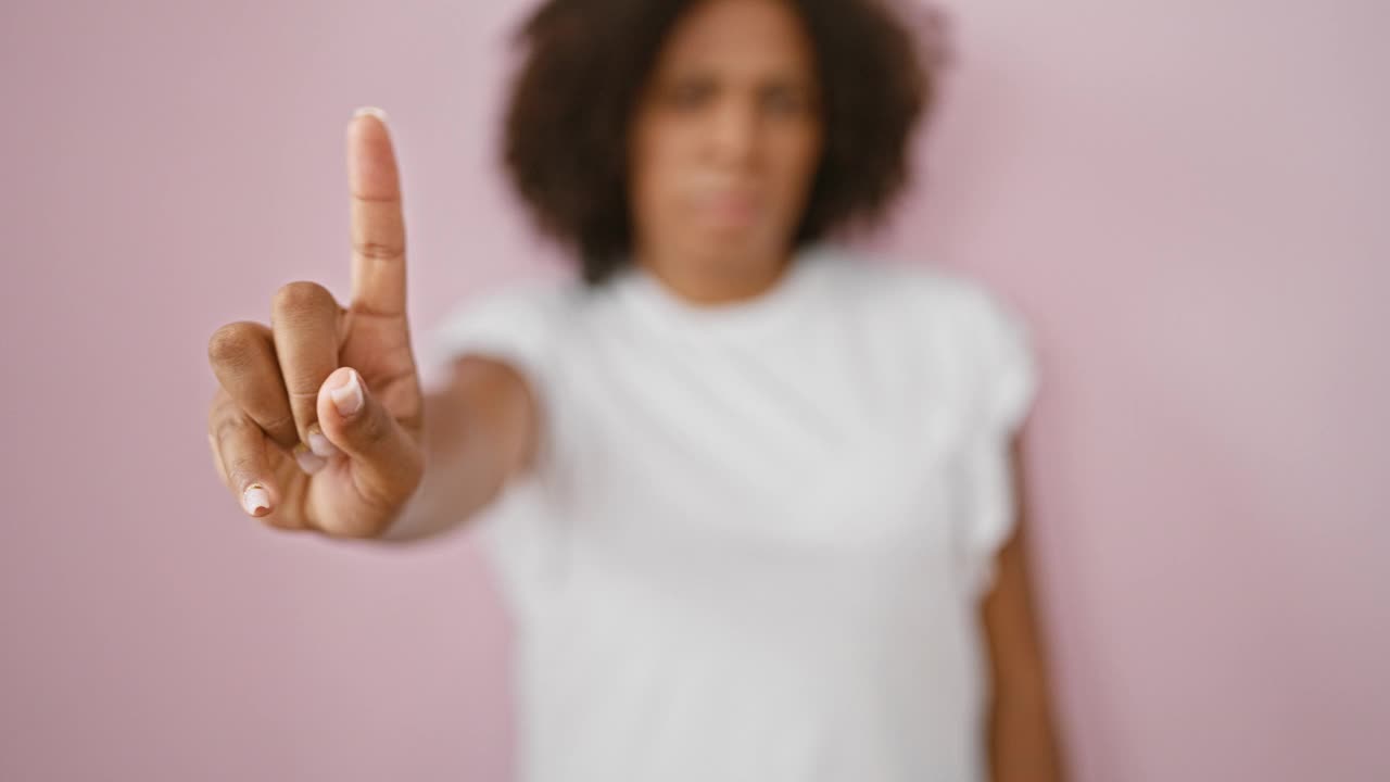 在粉红色的背景下，扎着辫子的黑人女人做着“不”的手势视频素材