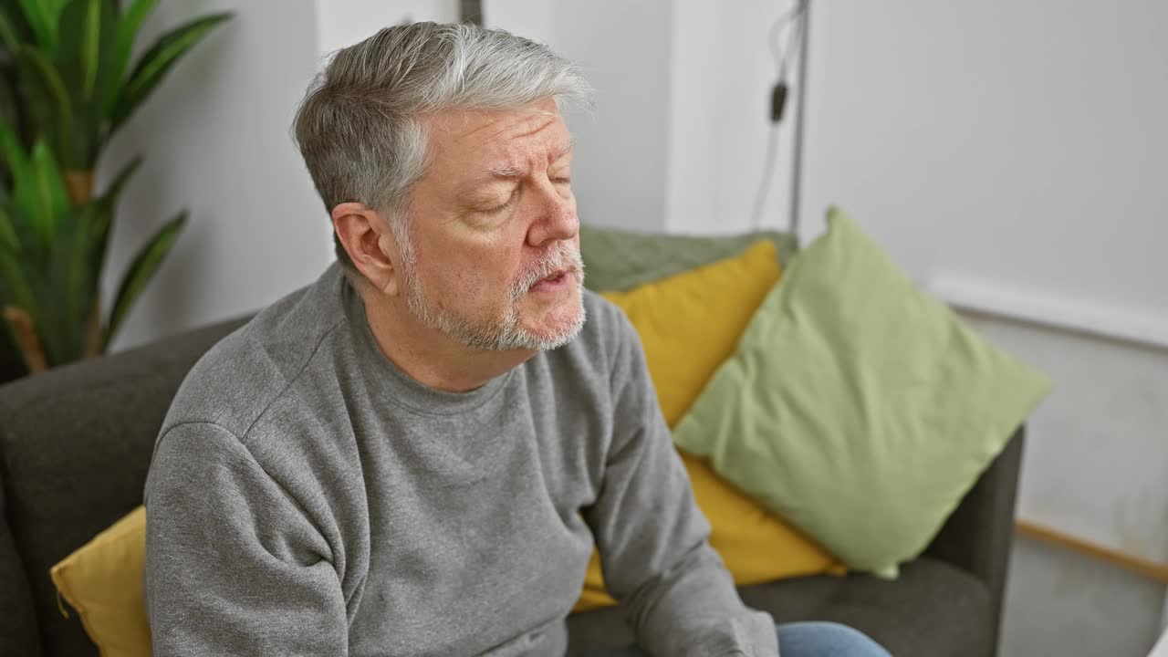 一位白发苍苍、忧心忡忡的老人若有所思地坐在客厅的沙发上，唤起人们沉思或担忧的主题视频素材