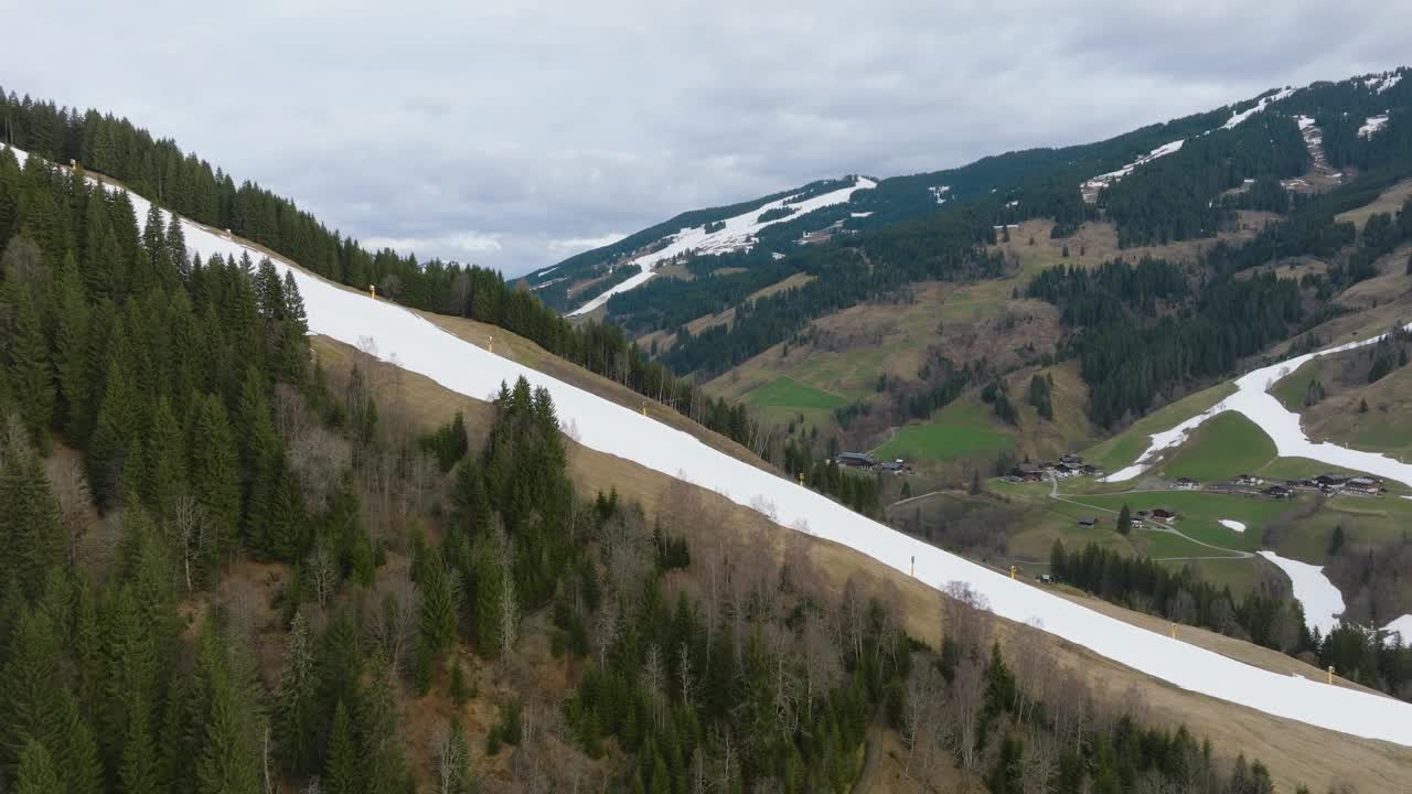 在saalbach - hinterglmm(奥地利)山坡上融化的雪，斑驳的绿色，航拍视频素材