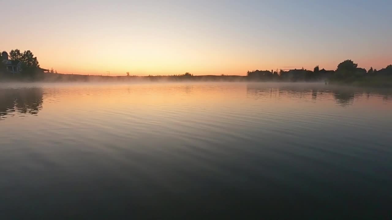 在寒冷的天气里，甜蜜多彩的日出或日落在湖上。冬天的景色。剪影木码头。乡村地区令人放松的风景。粉红色的天空映在平静的水面上视频素材