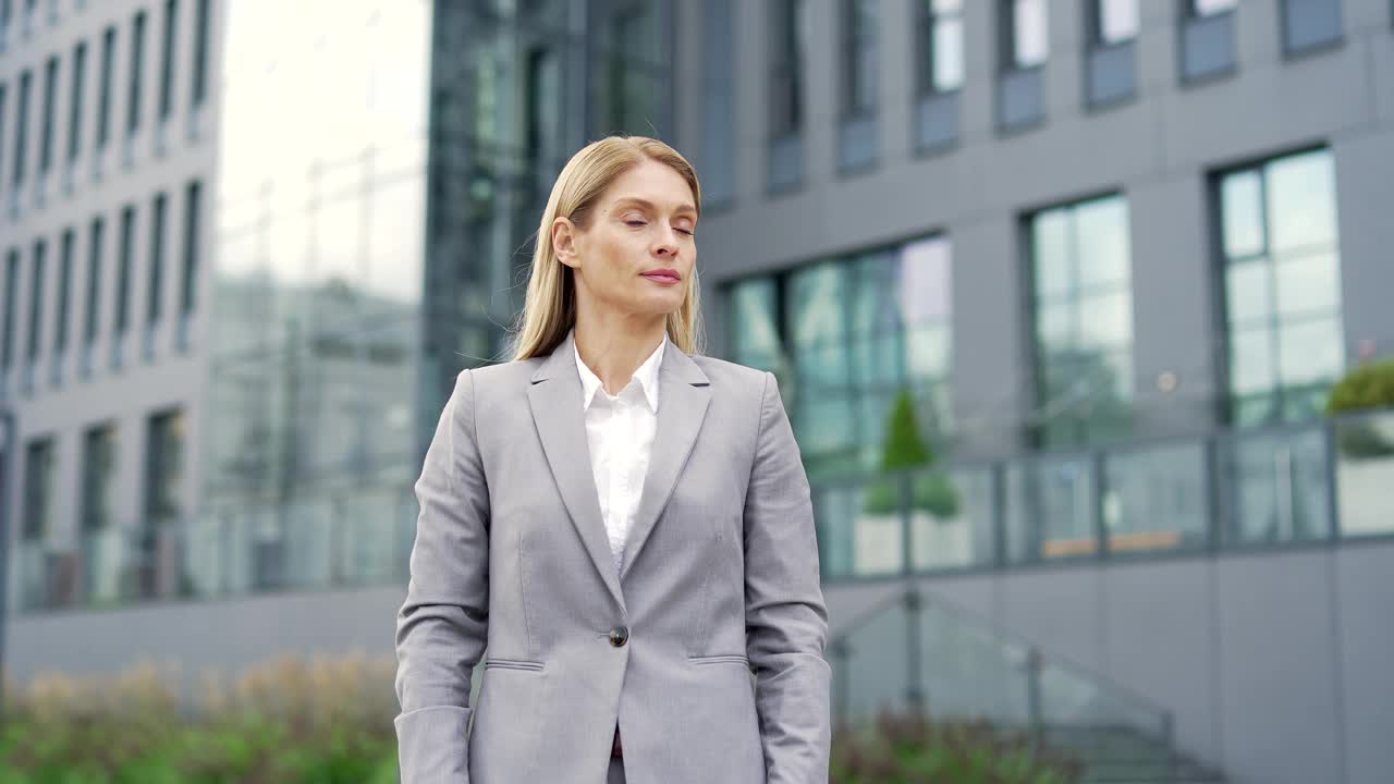 一位快乐的女商人站在办公楼附近的街道上。视频素材