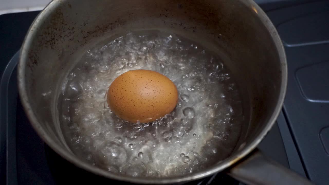 在锅里煮鸡蛋。近距离拍摄在不锈钢锅中煮鸡蛋时沸腾的水视频下载