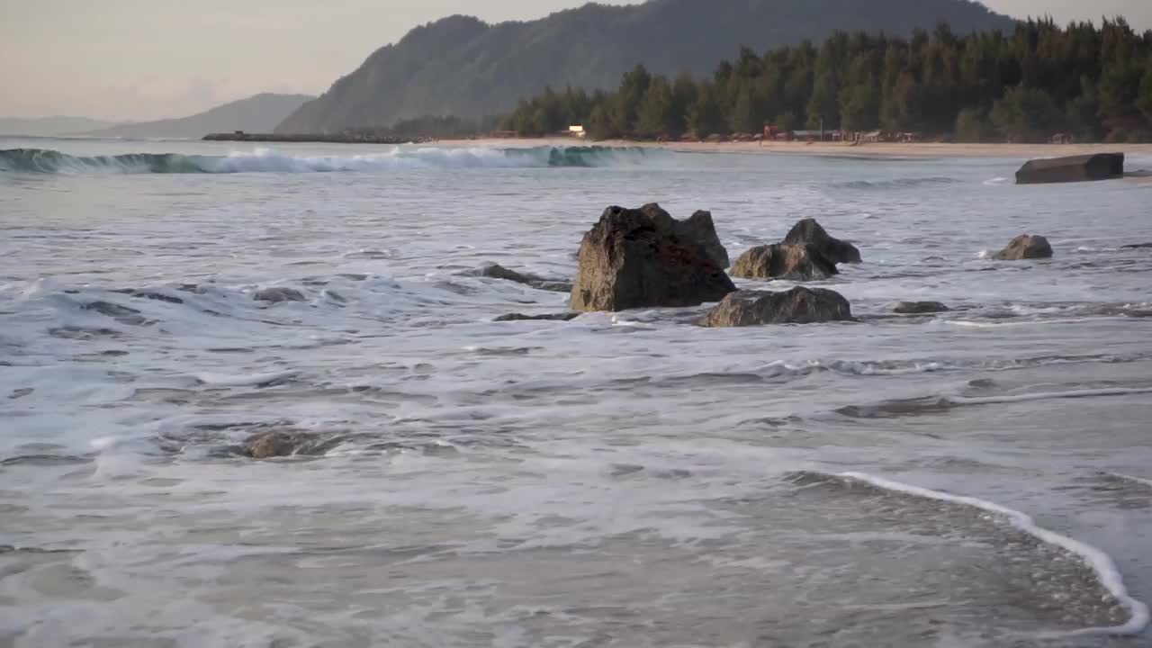 海浪拍打着印度尼西亚班达亚齐兰普克海滩上巨大的堤道石头。亚齐的热门旅游目的地。视频下载