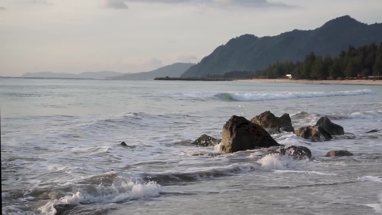 海浪拍打着印度尼西亚班达亚齐兰普克海滩上巨大的堤道石头。亚齐的热门旅游目的地。视频素材