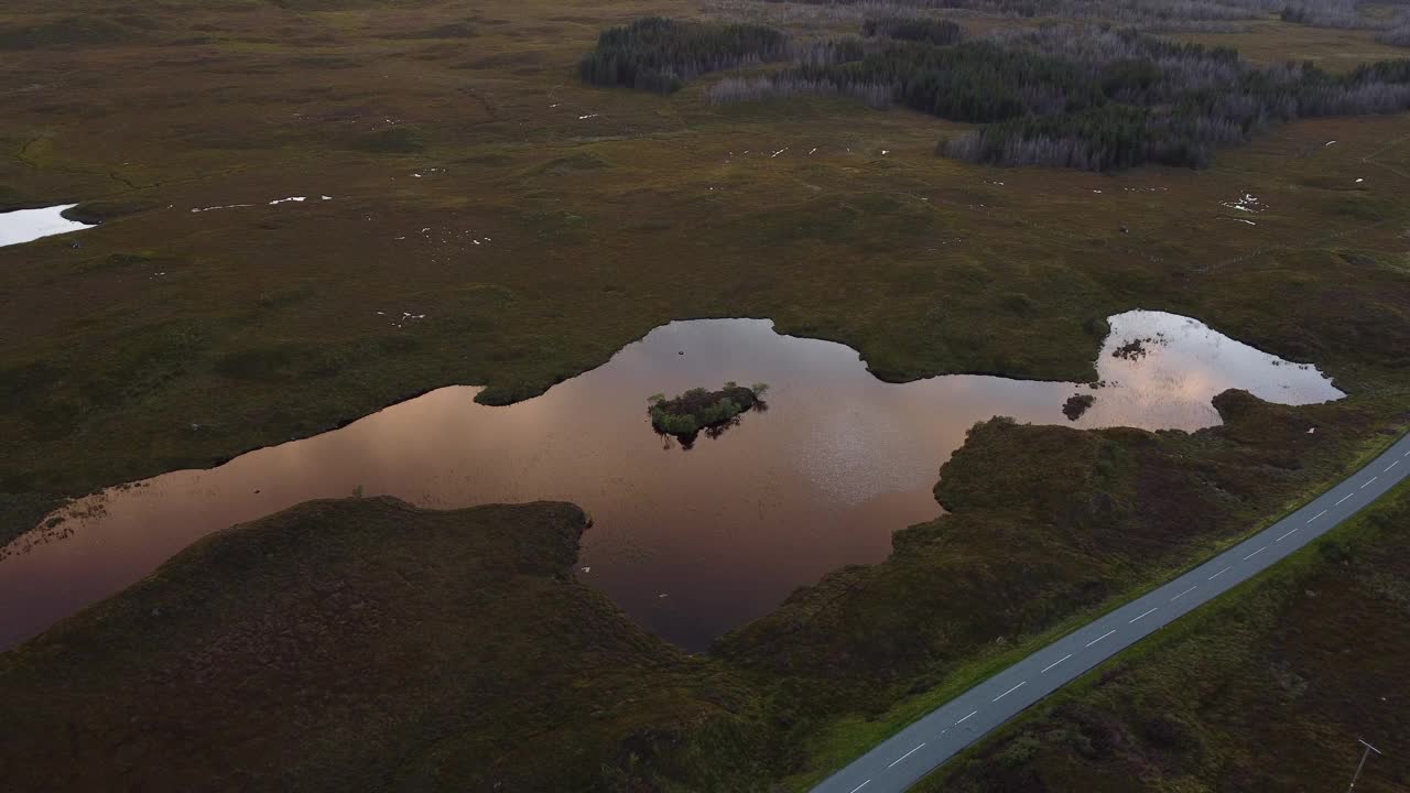 天空上方的空中景观反映在乡村湖在斯凯岛，苏格兰道路穿过田野视频素材