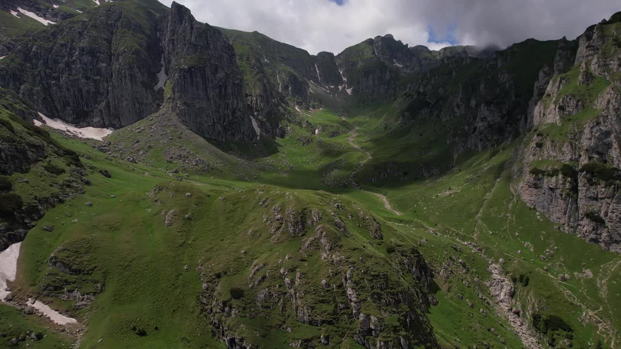 郁郁葱葱的绿色山谷坐落在布塞吉山峰之间，有着清澈的蓝天和崎岖的地形视频素材