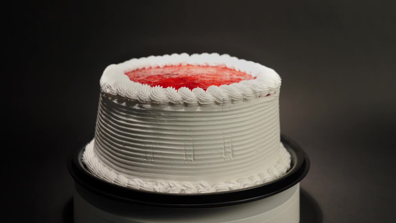 草莓浆果果冻蛋糕用奶油在一个黑色背景的旋转桌环可口治疗甜好吃视频素材
