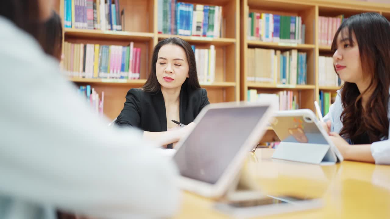 三个女人坐在图书馆的一张桌子旁，正在做一个项目视频素材