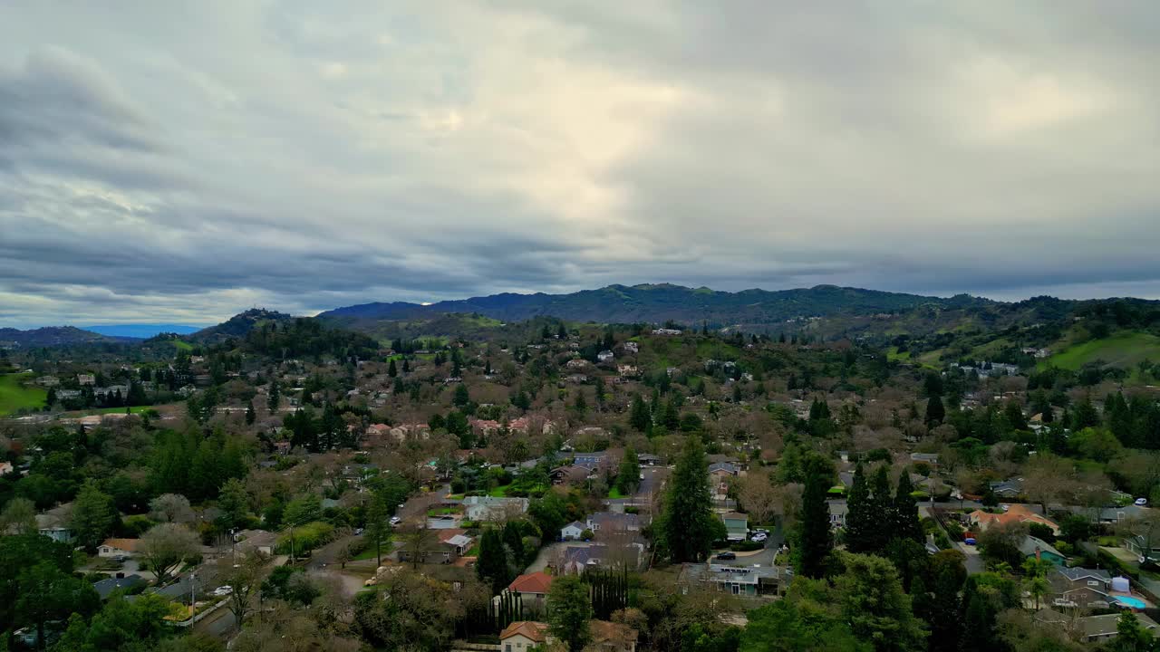 一个住宅区的鸟瞰图，坐落在丘陵地带，天空和地平线上乌云密布视频素材