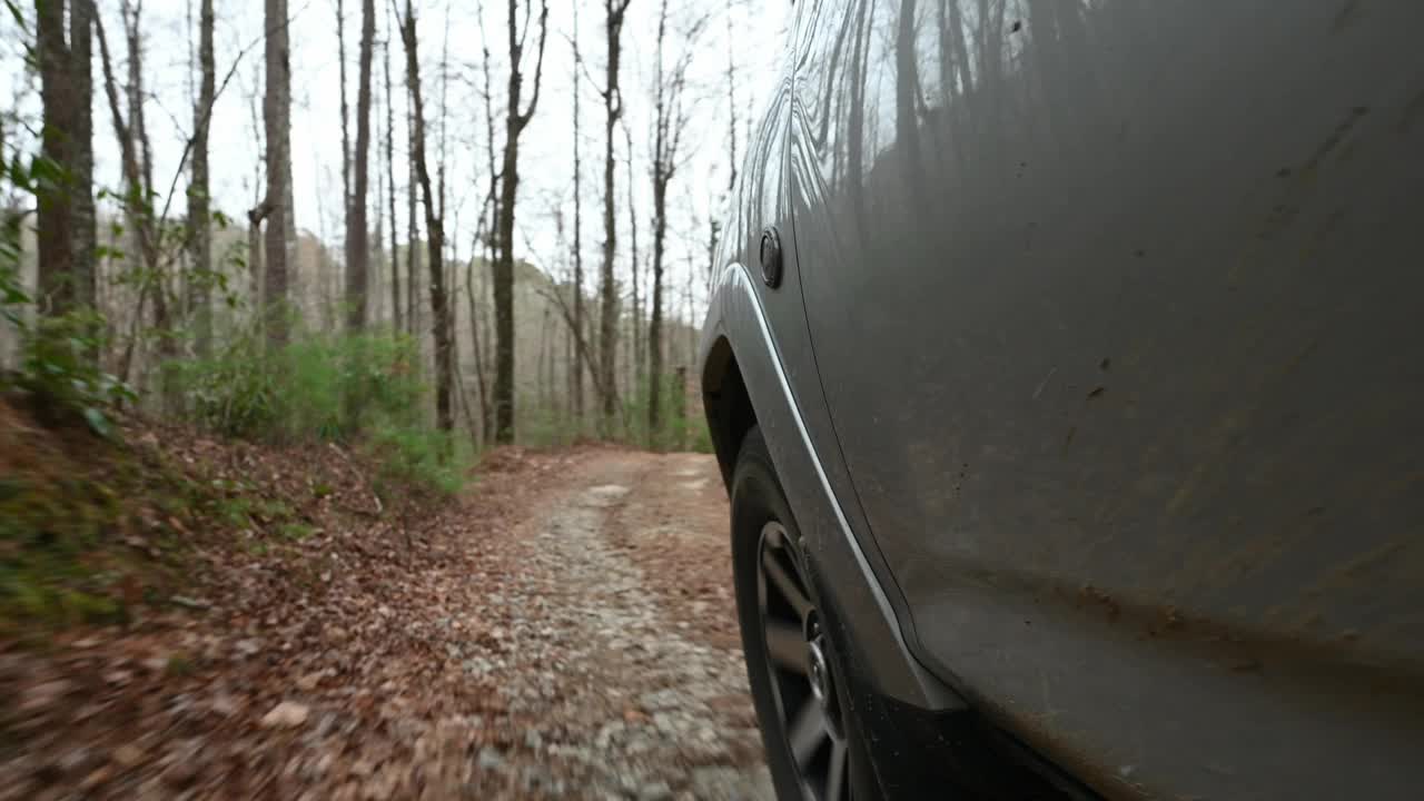 在森林的乡村道路上行驶时，车辆的轮胎视图视频下载