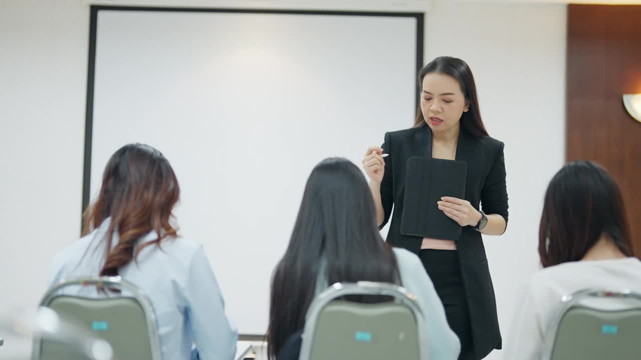 一位女士正在会议室里给一群女士做报告视频素材