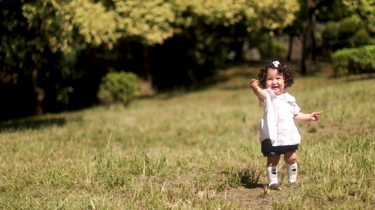 在公园里，一个一岁的小女孩走向她的妈妈。视频素材