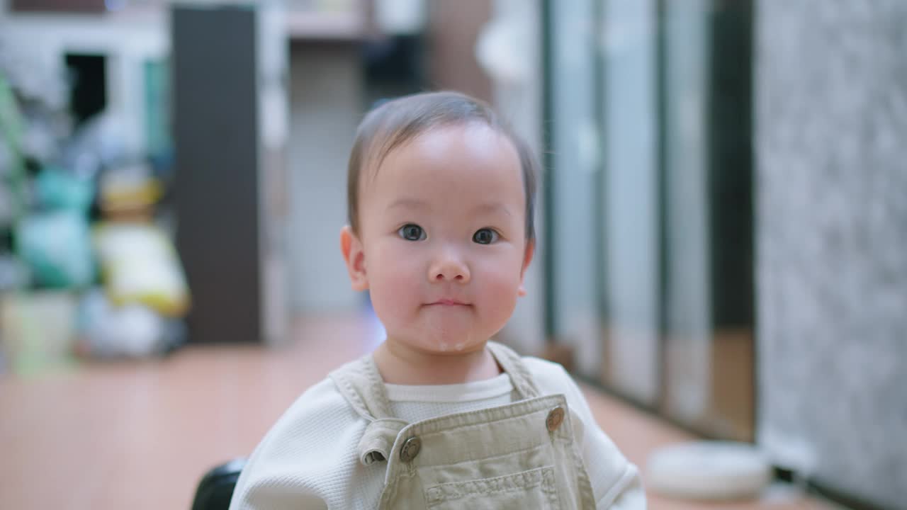 一个蹒跚学步的孩子面带微笑地看着镜头，嘴里吐着口水视频素材